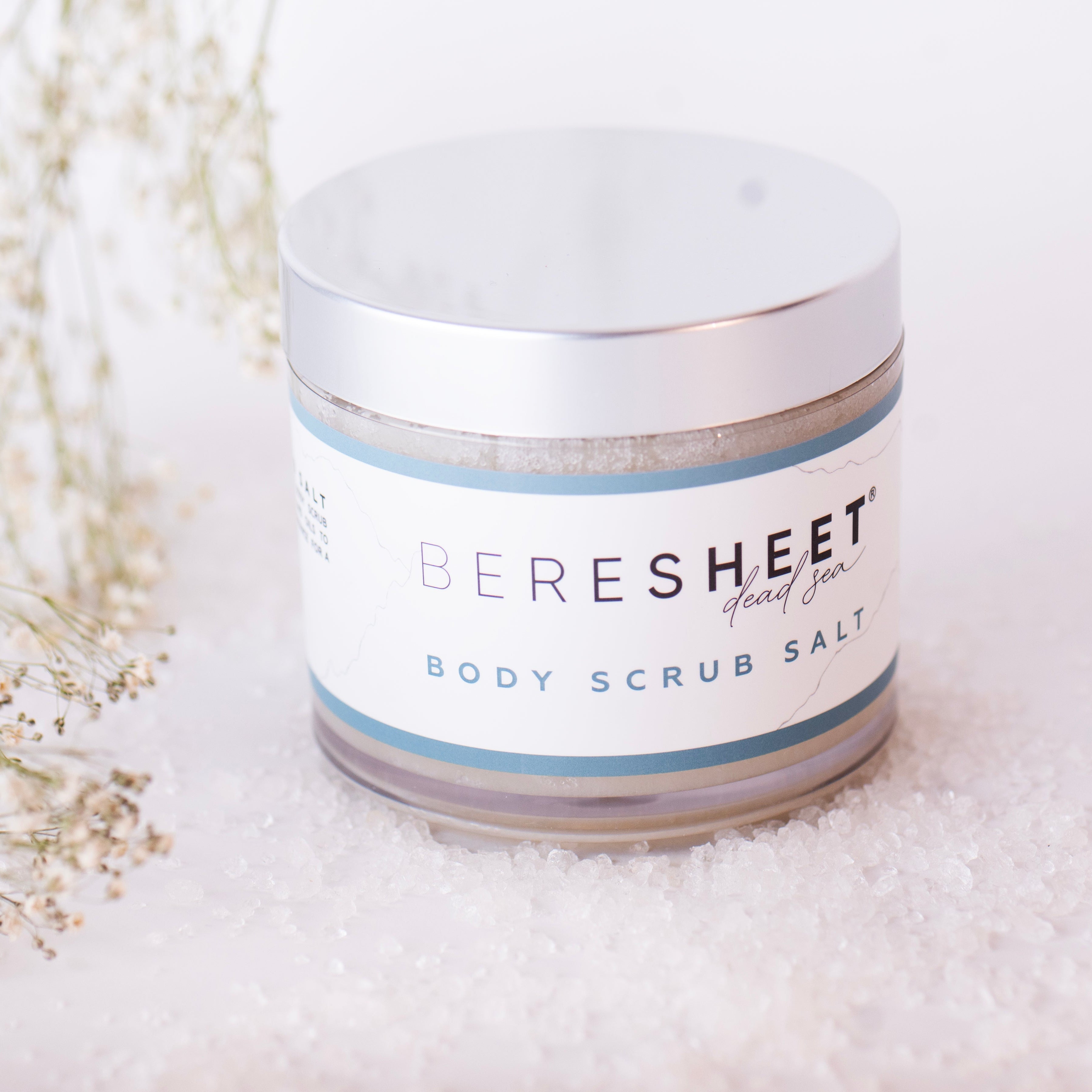 Jar of 'Beresheet' body scrub salt on a white background with dried flowers.