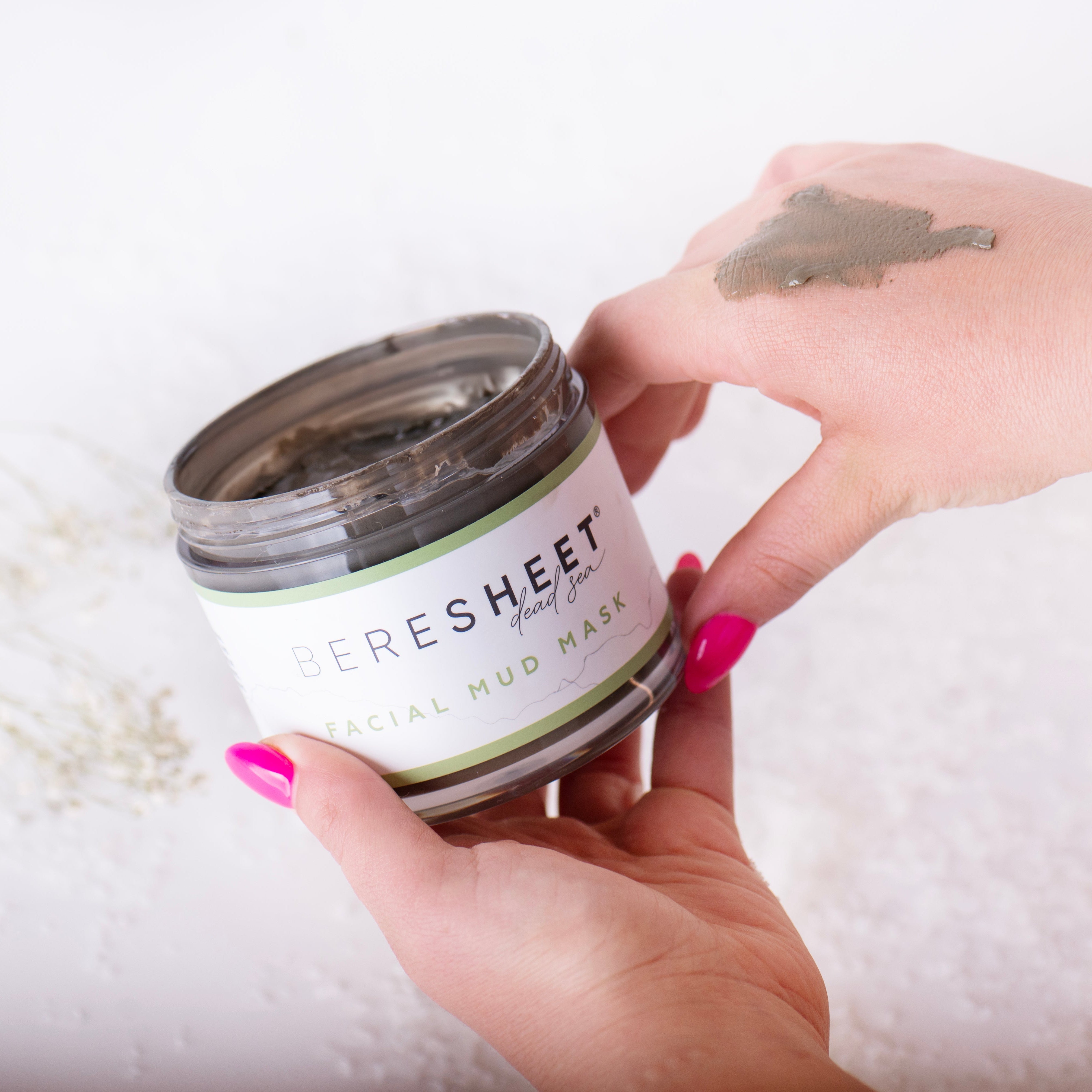 Person holding a jar of 'Beresheet' crystal mud mask with a white background