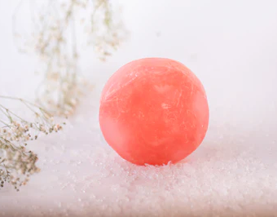 Pink bath bomb on a white surface with dried flowers