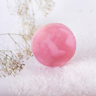 Pink bath bomb on a white surface with small flowers