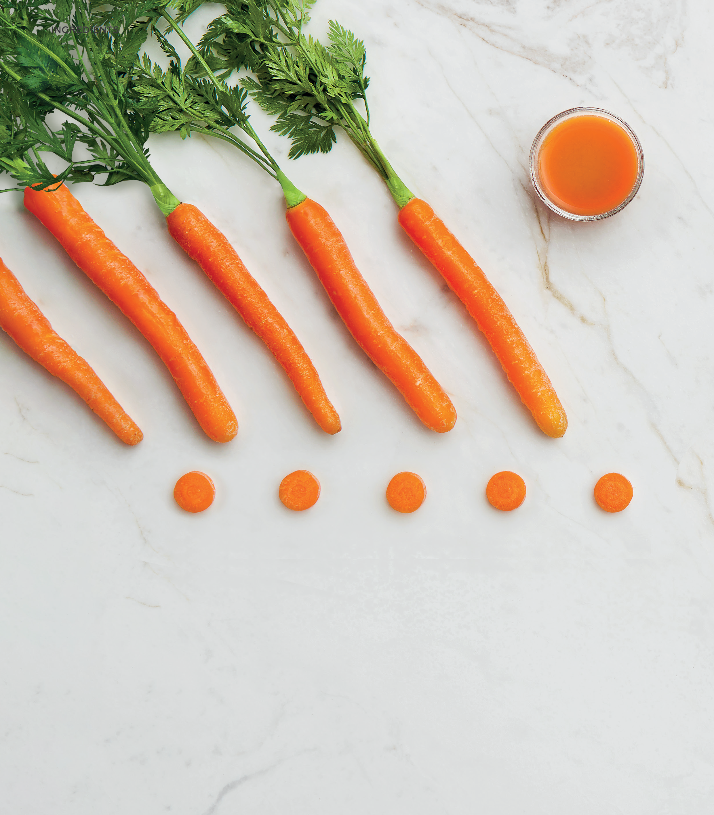Carrots with green tops on a light marble background