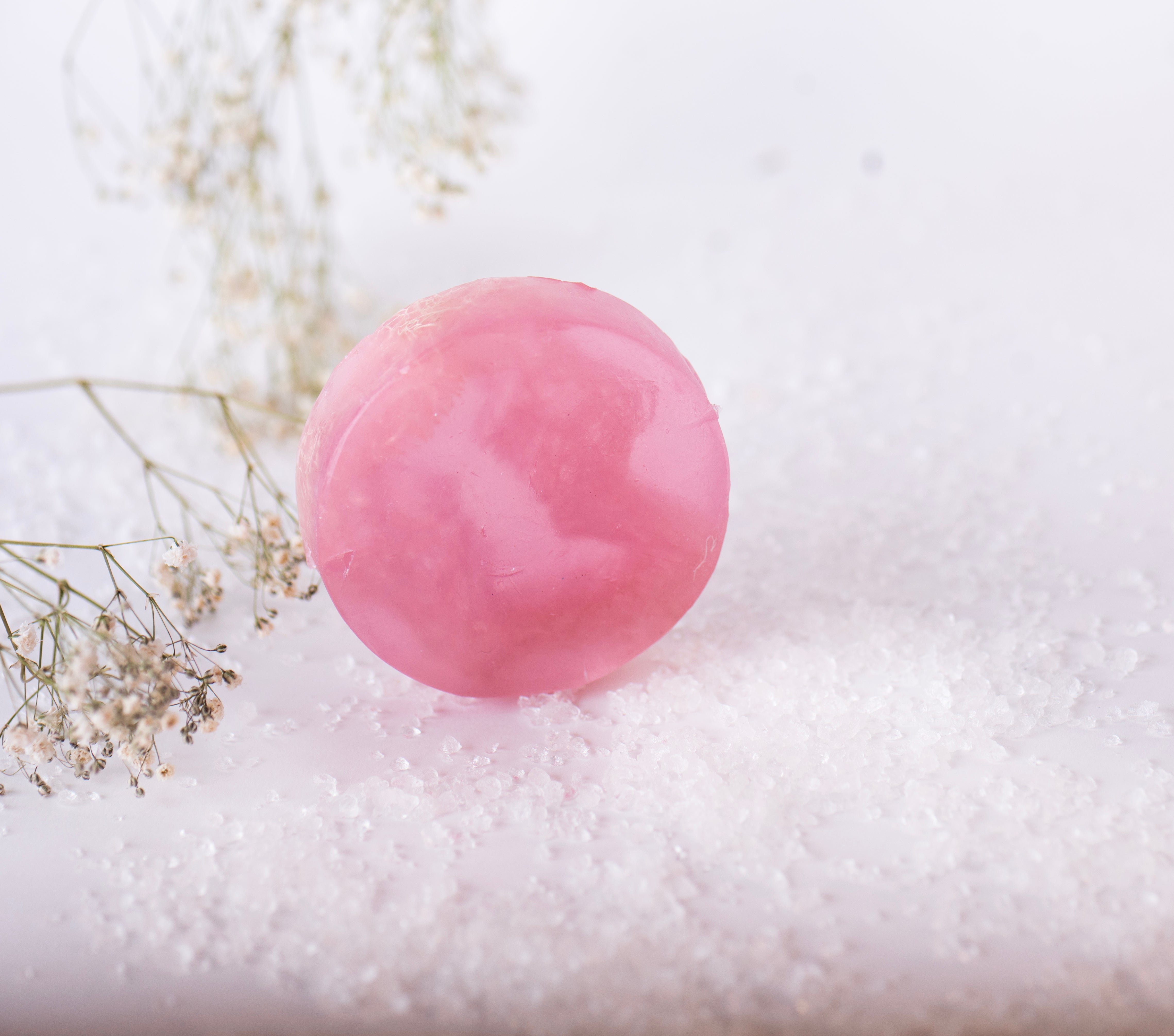 Pink bath bomb on a white surface with small flowers