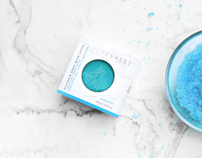 Blue bath bomb with packaging on a marble surface