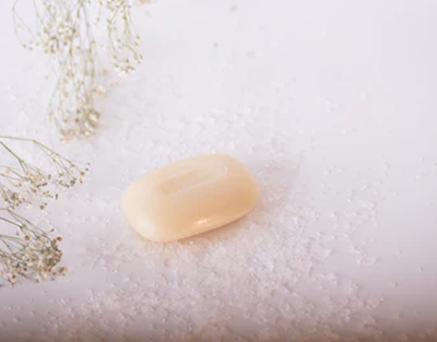Bar of soap on a white surface with dried flowers