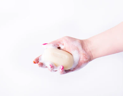 Hand holding a bar of soap with a white background