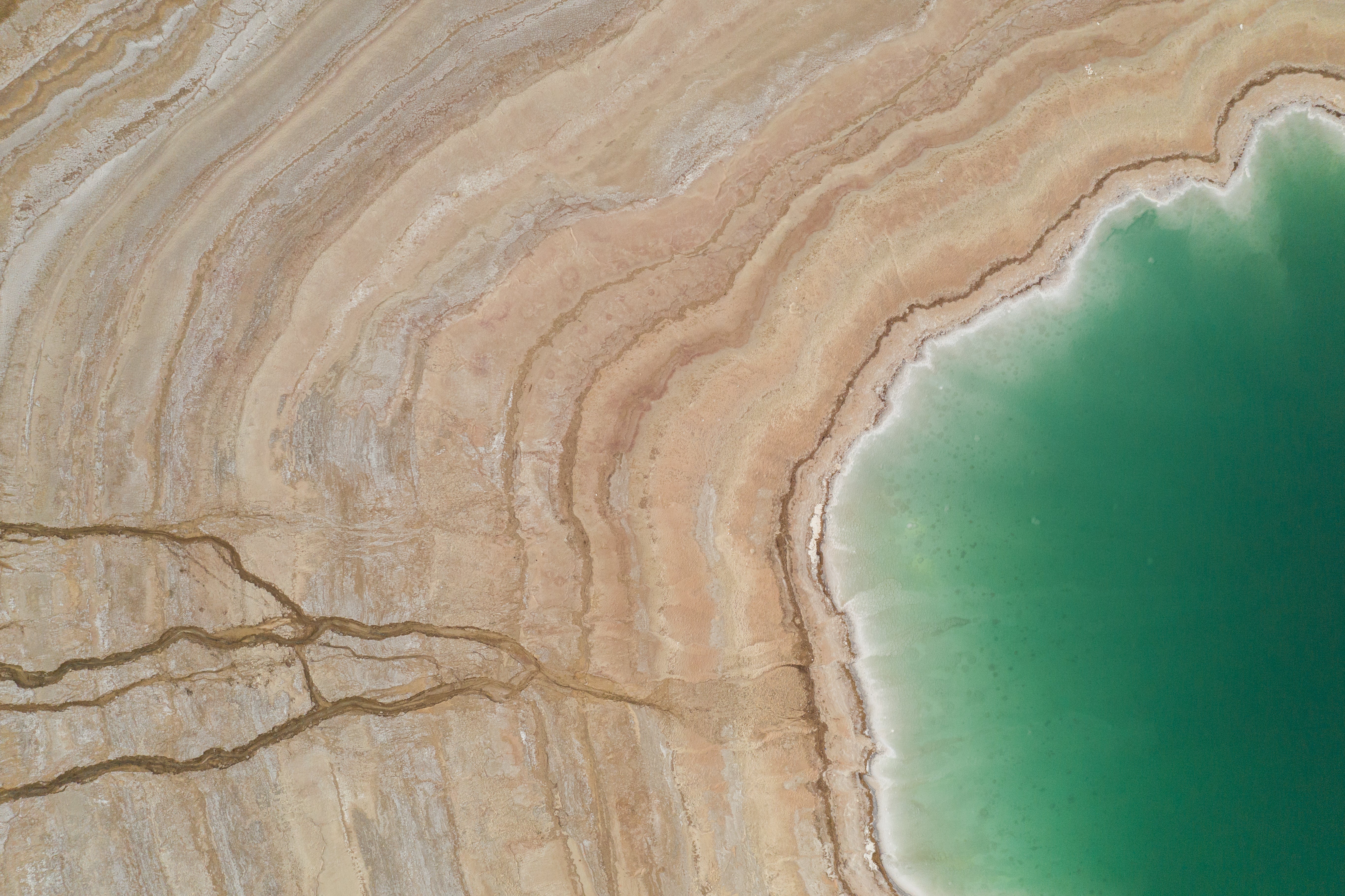 Dead Sea coastline with green water and beige sand.