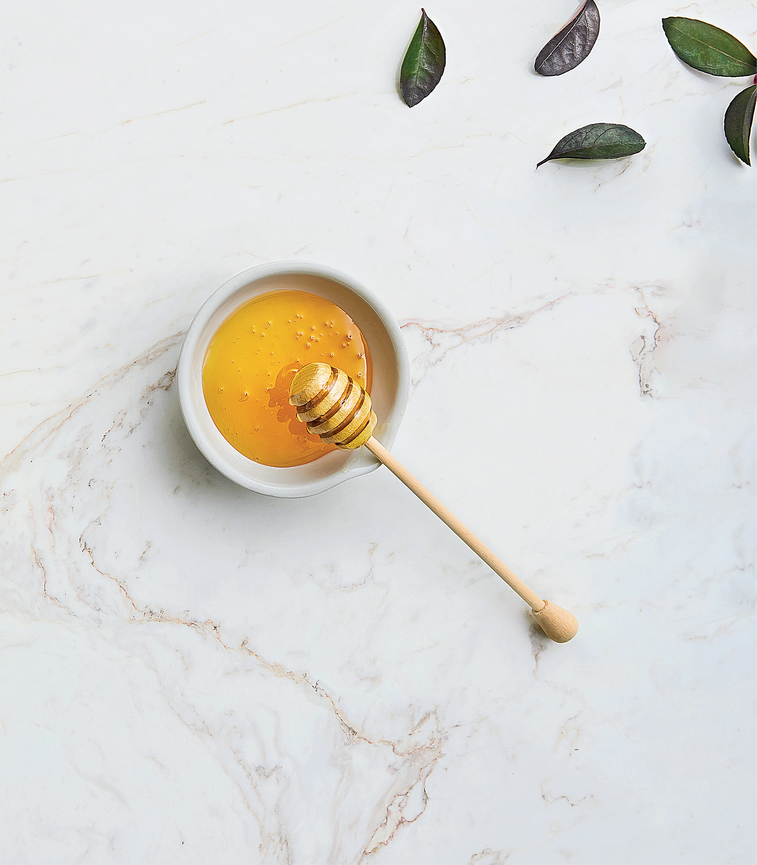 Honeycomb with honey in a white bowl on a marble surface