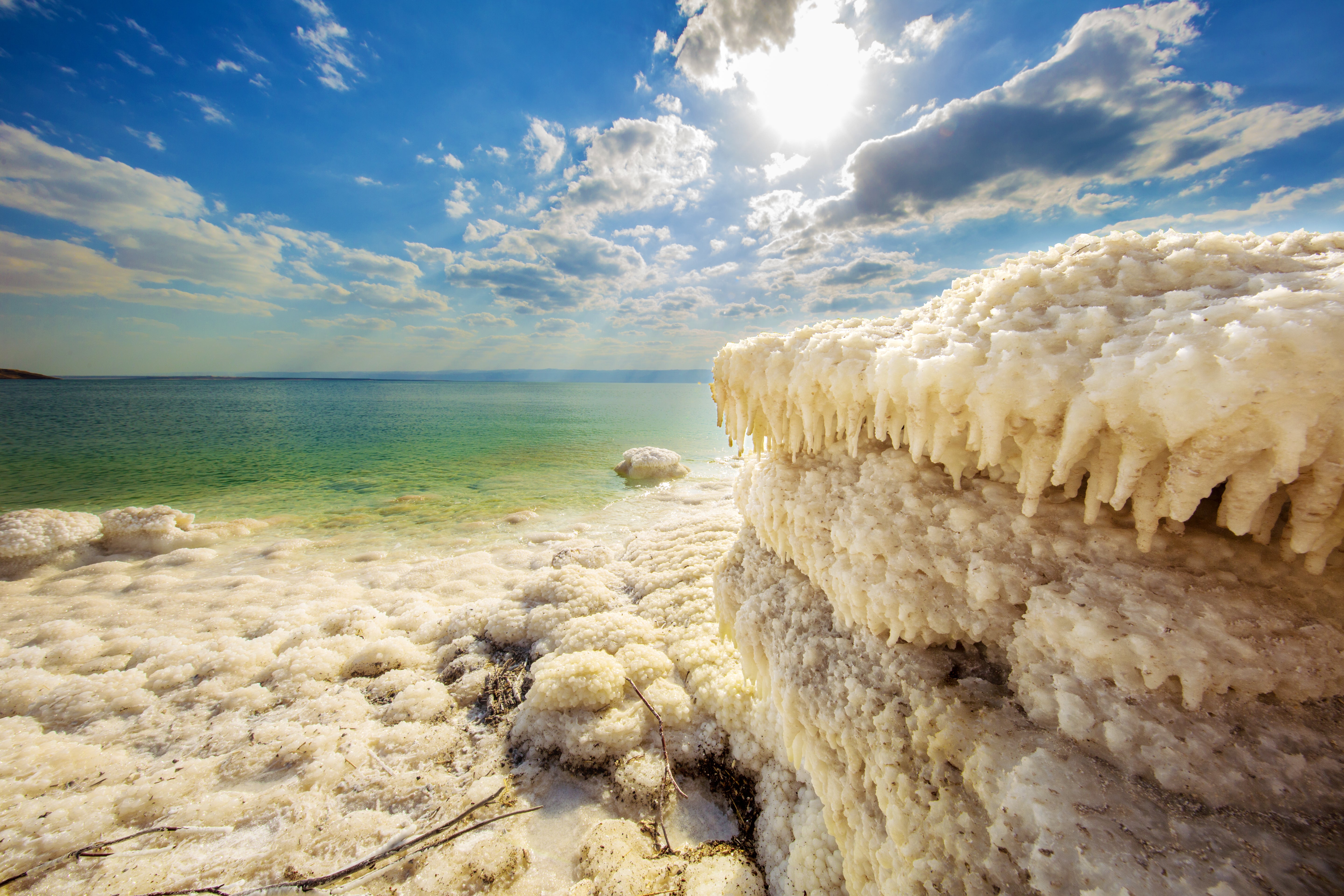 Dead Sea coastline with salt formations and blue sky.