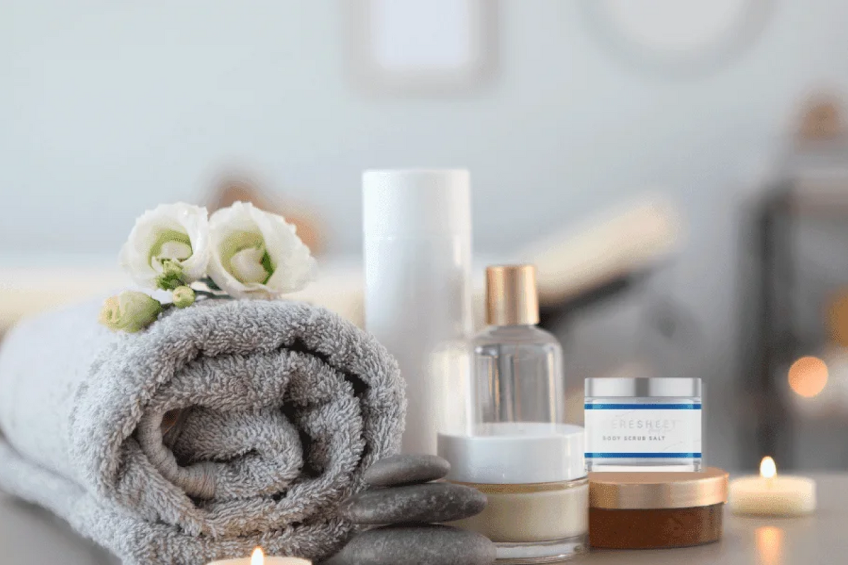 Towel, candles, and skincare products on a blurred background